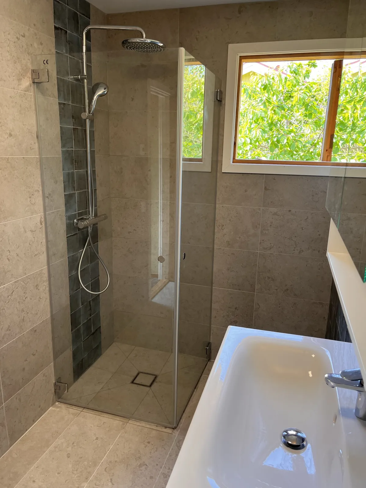 Badrumsrenovering i Harplinge – Duschplats med mörkgröna kakelplattor och fönster i badrummet